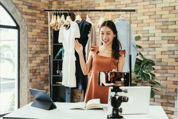woman filming at home studio with fashion behind her